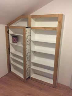 an open bookcase in the corner of a room with wooden floors and white walls