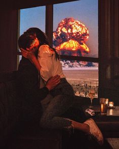 a man and woman sitting on a couch in front of a window with an explosion behind them