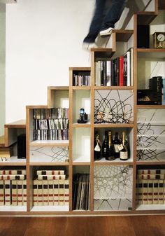 a book shelf filled with lots of books next to a wall mounted wine bottle rack