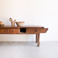 a wooden table with bowls and spoons sitting on it's side, in front of a white wall