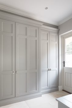 an empty room with white cupboards and drawers on the wall, in front of a window