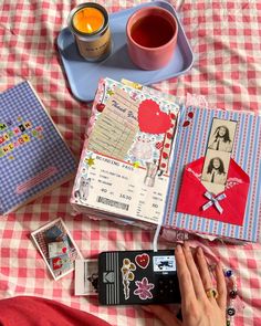 a person is laying on a bed with many things in front of them, including an open book and cup of tea