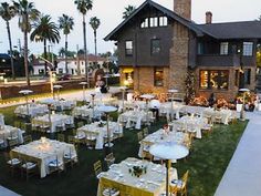 tables and chairs are set up in front of a house with lights on the lawn