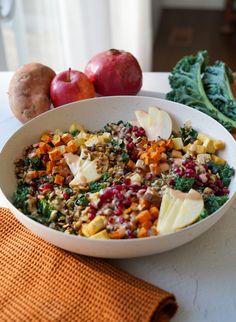 a white bowl filled with lots of food next to other fruits and vegetables on top of a table