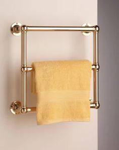 a gold towel rack with two towels hanging from it's sides and a yellow towel on top