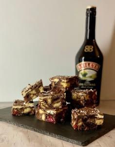 some brownies are stacked on top of each other next to a bottle of beer