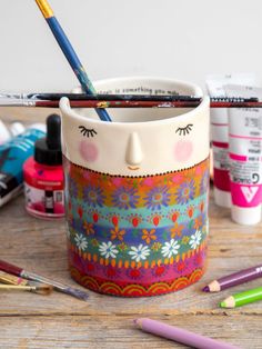 a cup that has some paint and pencils in it