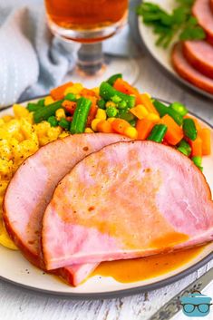 ham, vegetables and corn on a plate with a glass of beer in the background