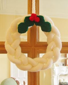 a white wreath hanging from a cross on top of a window sill next to a stuffed animal