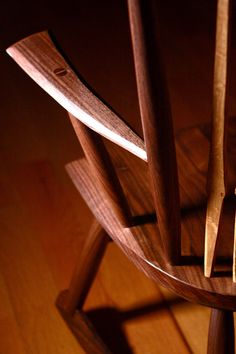 a wooden chair that is on top of a hard wood floor with light coming in from behind it