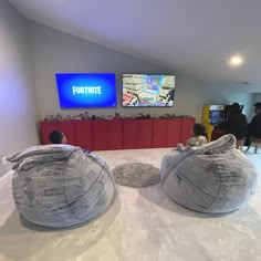 two children sitting on bean bags in front of a tv