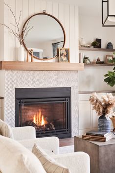 a living room filled with furniture and a fire place in front of a mirror on the wall