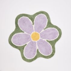 a purple and green rug with a flower on it's center, sitting on a white surface