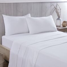 a bed with white sheets and pillows on it