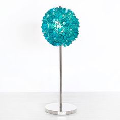 a blue flower on a metal stand with a white wall in the backround