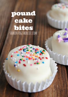 two white cakes with sprinkles on them sitting on top of a wooden table