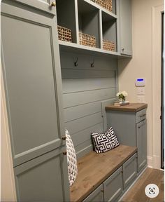 a room with gray cabinets and wooden bench