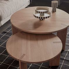 two wooden tables sitting on top of a rug in a living room next to a couch