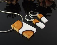 two pieces of wood and white acrylic are hanging from a necklace on a black surface