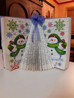 an open book with snowmen on it sitting on top of a white countertop