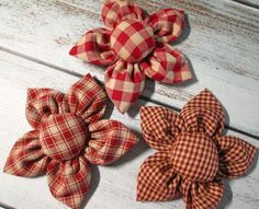 three red and white checkered fabric flowers sitting on top of a wooden table next to each other