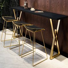 three stools and a table in front of a wooden wall