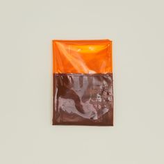 an orange and brown bag sitting on top of a white wall