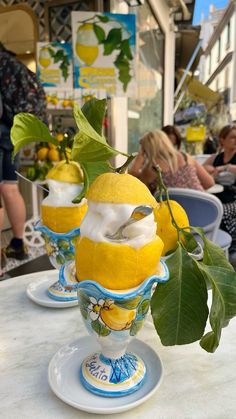 three lemons are sitting in cups on a table with people seated at tables behind them