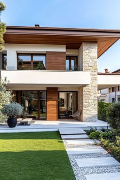 a modern house with grass and trees in the front yard