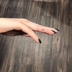 a woman's left hand with a small tattoo on her thumb and the number 22