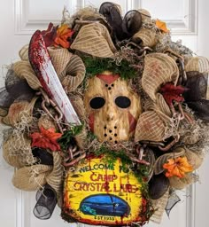 a halloween wreath with a hockey mask on it and an old sign that says welcome to camp cootie