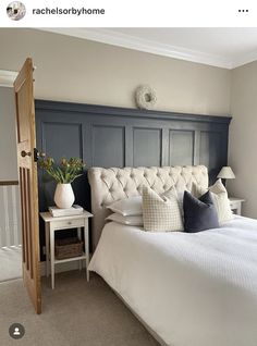 a white bed sitting in a bedroom next to a wooden headboard