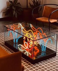 a glass table with neon lights on it in a room filled with chairs and couches