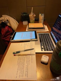 two laptops sitting next to each other on a table with papers and pens in front of them