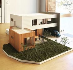 a model of a house with grass on the ground and a car parked in front of it