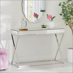 a white console table with pink flowers and a mirror on the wall in front of it