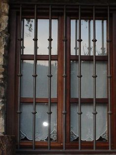 a cat sitting on the ledge of a window with bars in it's windowsill