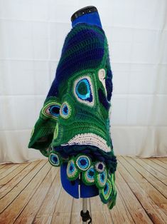 a blue and green crocheted hat with peacock feathers