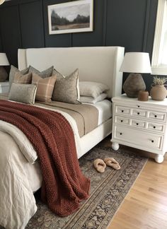 a bed with pillows and blankets on top of it in a bedroom next to two lamps