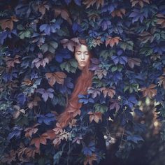 a painting of a woman with long red hair surrounded by leaves