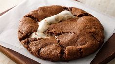 a chocolate cookie with white icing sitting on top of a piece of parchment paper