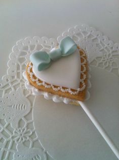 a heart shaped cookie on a white doily with a toothpick in the shape of a heart