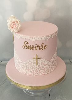 a pink cake with white lace and a cross on the top that says savore