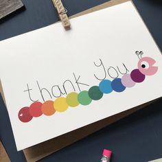 a thank you card with the word rainbow painted on it next to some crayon markers