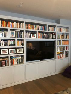 a living room with bookshelves and a flat screen tv mounted on the wall