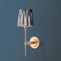 a wall light with a lamp shade on it's side against a blue background