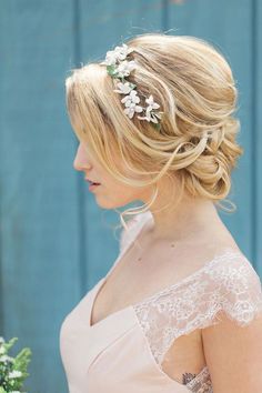 a woman with blonde hair wearing a bridal hairstyle and flowers in her hair