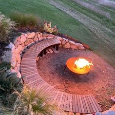 an outdoor fire pit surrounded by rocks and grass