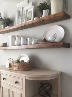 two wooden shelves above a table with plates and cups on it, one shelf is holding dishes