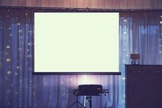 a large screen in the corner of a room next to a lamp and some lights